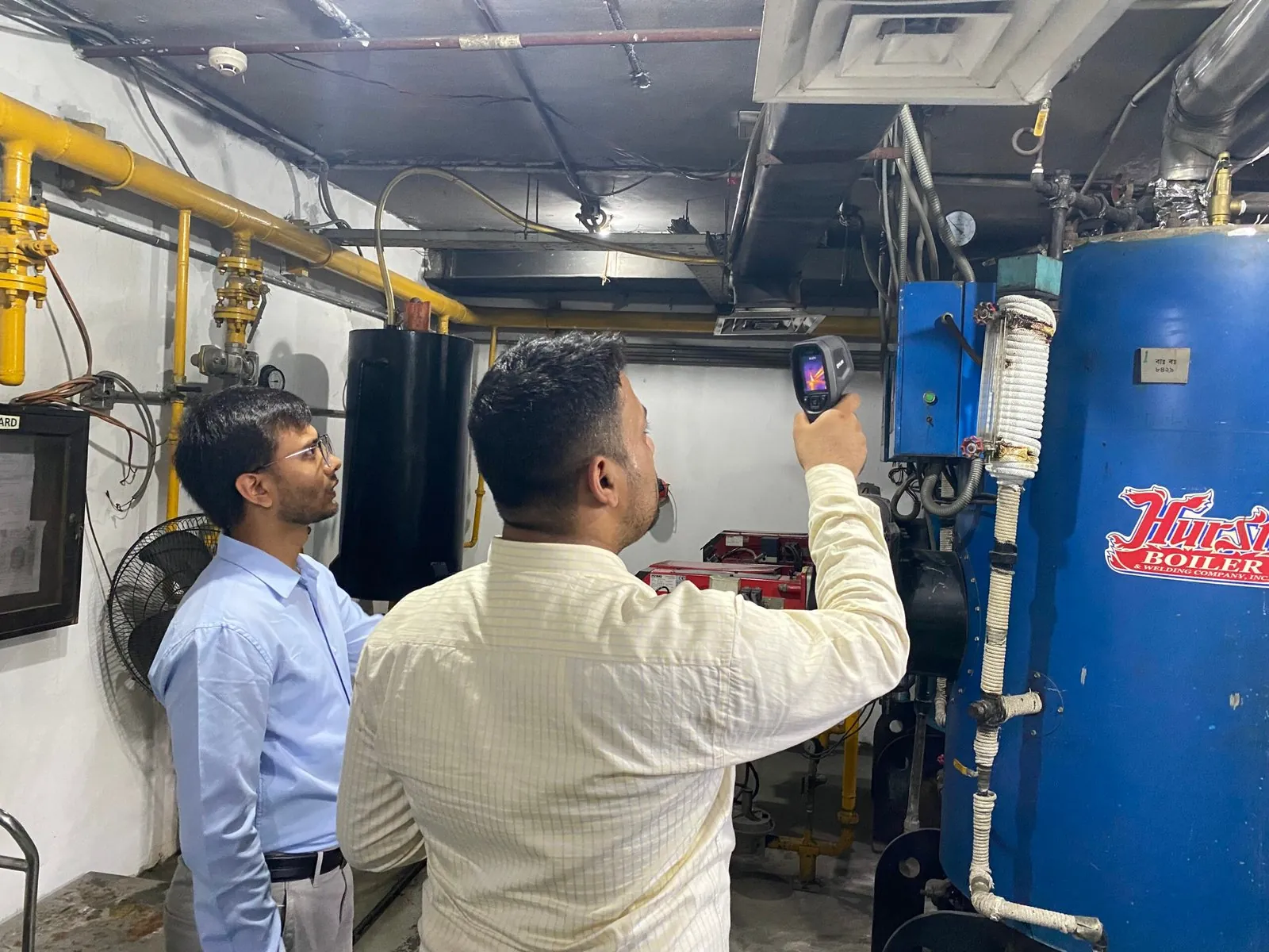 Engineers surveying a boiler with a thermal camera